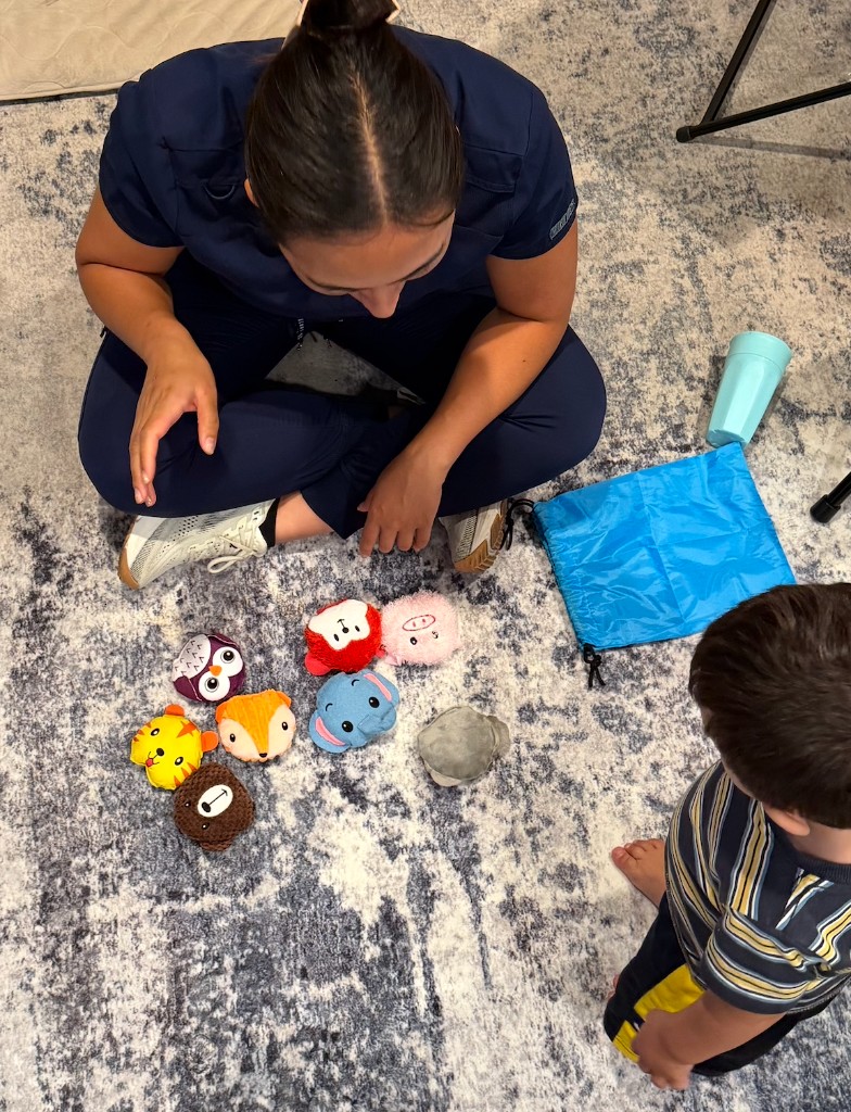 Janet Han sitting on the floor with a child during a play-based therapy session